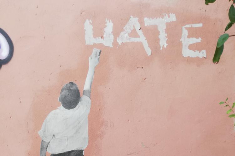 Person erasing 'hate' graffiti