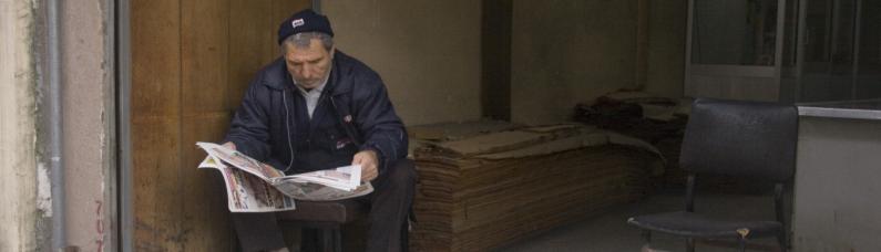 Ein Mann in einem zerfallenen Lokal liest Zeitung