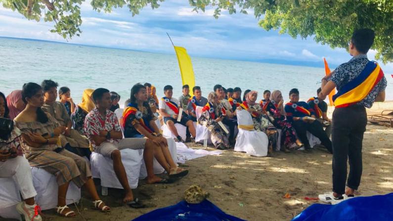 Members of the Responsible Young Leaders Organization listen to a speaker on the beach