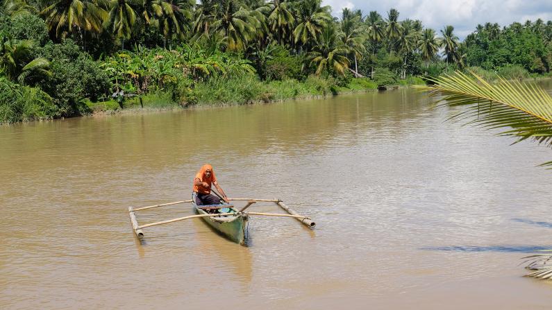 A villager crosses the murky Hijo river on his canoe