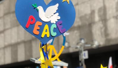 Title of the annual report of forumZFD with a blue heartshaped sign of a dove and the coloured word peace.