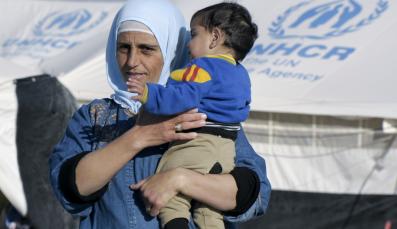 Mutter hält Kind vor Zelt für Flüchtlinge