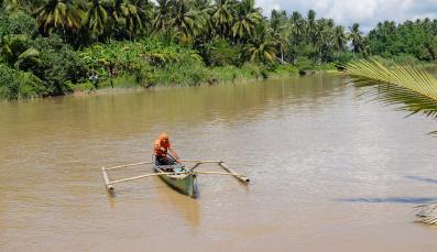A villager crosses the murky Hijo river on his canoe